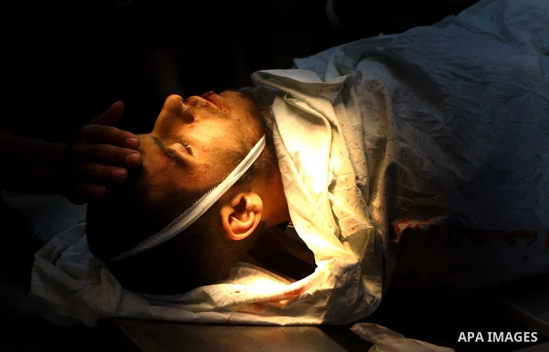 Palestinian men carry the body of Mohammed Enaya at the mortuary of Al-Shifa hospital after he was killed when the Israeli air force targeted an area in the eastern part of Gaza City on August 19, 2011. Photo by Ashraf A...