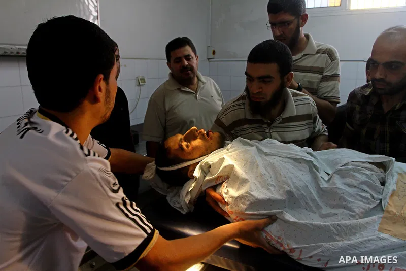 Palestinian men carry the body of Mohammed Enaya at the mortuary of Al-Shifa hospital after he was killed when the Israeli air force targeted an area in the eastern part of Gaza City on August 19, 2011. Photo by Ashraf A...