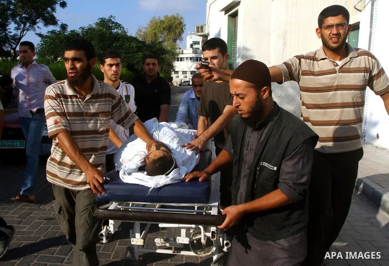 Palestinian men carry the body of Mohammed Enaya at the mortuary of Al-Shifa hospital after he was killed when the Israeli air force targeted an area in the eastern part of Gaza City on August 19, 2011. Photo by Ashraf A...