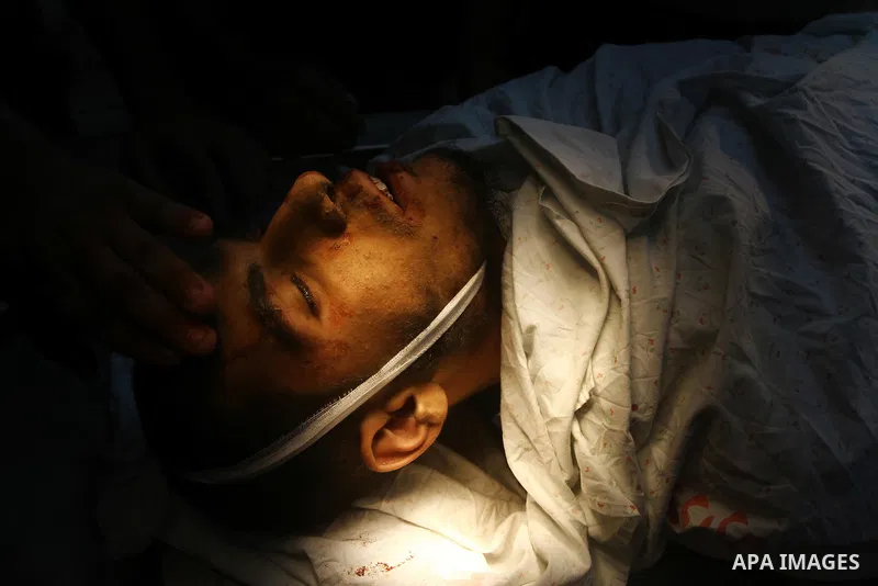 Palestinian men carry the body of Mohammed Enaya at the mortuary of Al-Shifa hospital after he was killed when the Israeli air force targeted an area in the eastern part of Gaza City on August 19, 2011. Photo by Ashraf A...