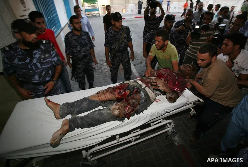 Palestinians carry a wounded boy into Al-Shifa hospital following Israeli air attacks, in Gaza City, Gaza Strip, 19 August 2011. Photo by Mahmud Nassar