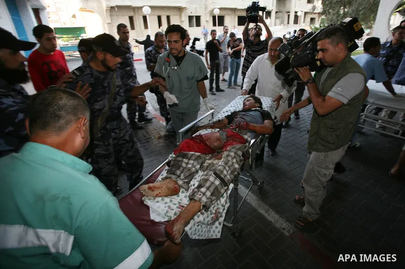 Palestinians carry a wounded boy into Al-Shifa hospital following Israeli air attacks, in Gaza City, Gaza Strip, 19 August 2011. Photo by Mahmud Nassar