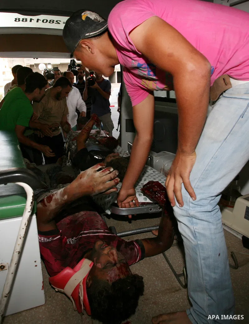 Palestinians carry a wounded boy into Al-Shifa hospital following Israeli air attacks, in Gaza City, Gaza Strip, 19 August 2011. Photo by Mahmud Nassar