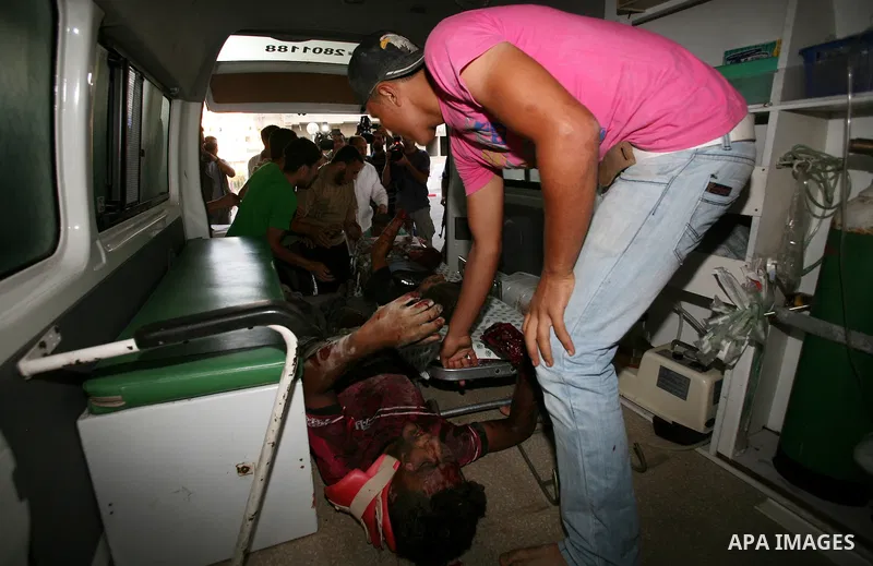 Palestinians carry a wounded boy into Al-Shifa hospital following Israeli air attacks, in Gaza City, Gaza Strip, 19 August 2011. Photo by Mahmud Nassar