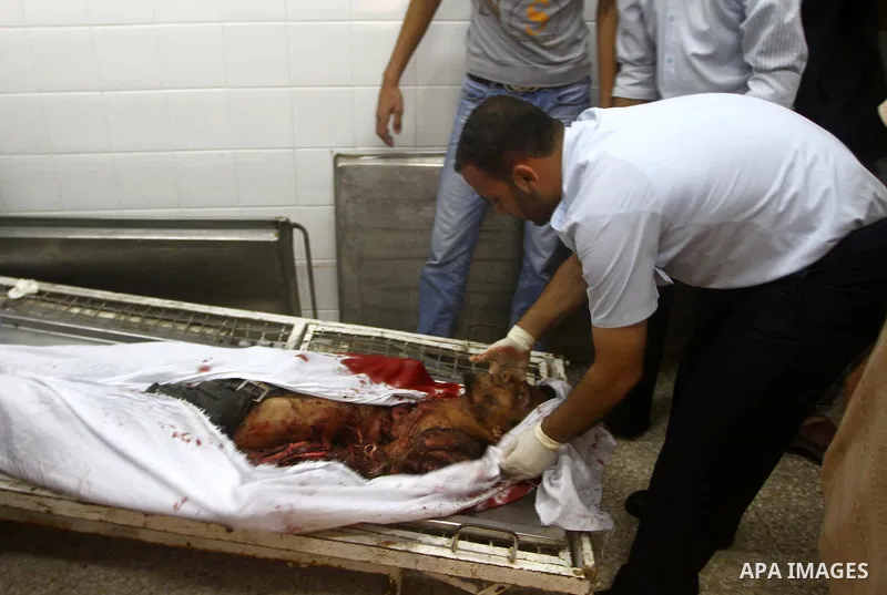 Palestinian men gather around the bodies of Emad Abu Abda and Anwar Isleem at the mortuary of Al-Aqsa hospital after they were killed when the Israeli air force targeted an area in the central Gaza Strip on August 19, 20...