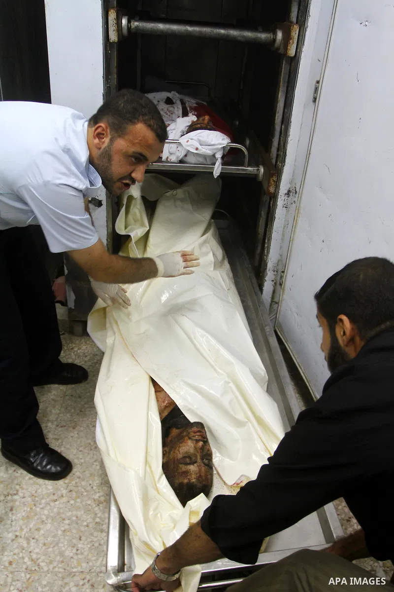 Palestinian men gather around the bodies of Emad Abu Abda and Anwar Isleem at the mortuary of Al-Aqsa hospital after they were killed when the Israeli air force targeted an area in the central Gaza Strip on August 19, 20...