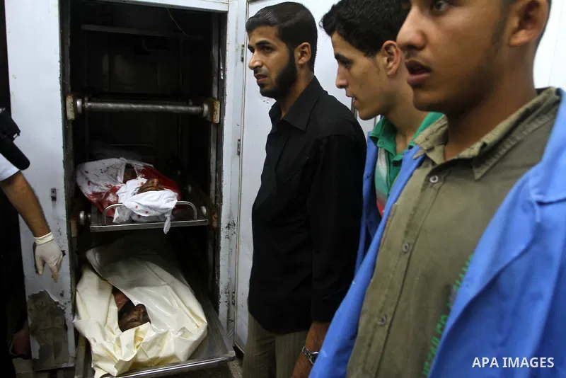 Palestinian men gather around the bodies of Emad Abu Abda and Anwar Isleem at the mortuary of Al-Aqsa hospital after they were killed when the Israeli air force targeted an area in the central Gaza Strip on August 19, 20...