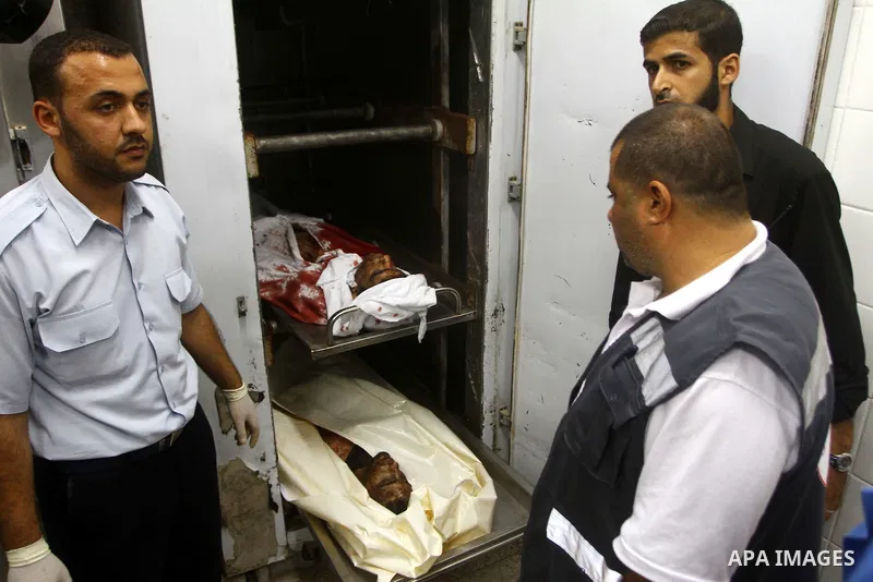Palestinian men gather around the bodies of Emad Abu Abda and Anwar Isleem at the mortuary of Al-Aqsa hospital after they were killed when the Israeli air force targeted an area in the central Gaza Strip on August 19, 20...