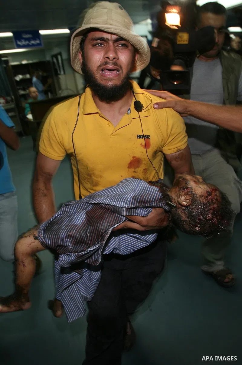 A Palestinian man carries the body of Islam Greagea, a five-year-old boy killed in an Israeli air strike, at a hospital in Gaza City on August 19, 2011. Three Palestinians were killed -- one of them a five-year-old boy -...