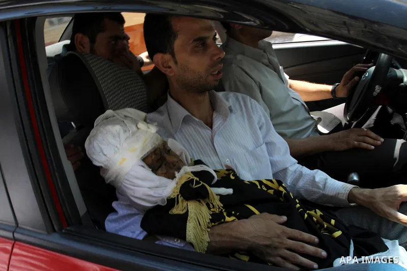 A Palestinian man carries the body of two-year-old boy Islam Qreqa during a funeral in Gaza City on August 20, 2011. Palestinians said at least nine militants have died in multiple Israeli strikes, as well as two childre...