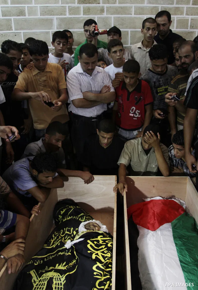 Palestinians mourn over the bodies of Moataz Qreqa, a commander of Islamic Jihad's Al-Quds Brigade, his five-year-old son Islam and his brother Munzer during their funeral in Gaza City on August 20, 2011 after all three...