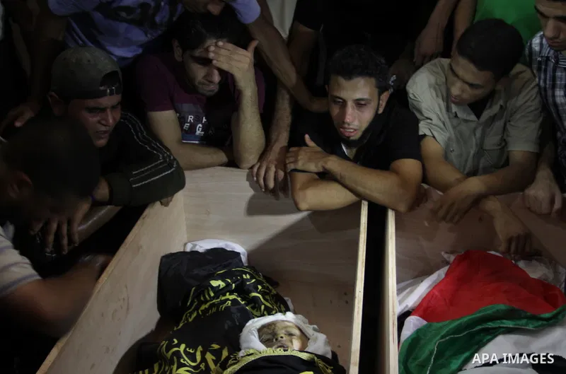 Palestinians mourn over the bodies of Moataz Qreqa, a commander of Islamic Jihad's Al-Quds Brigade, his five-year-old son Islam and his brother Munzer during their funeral in Gaza City on August 20, 2011 after all three...