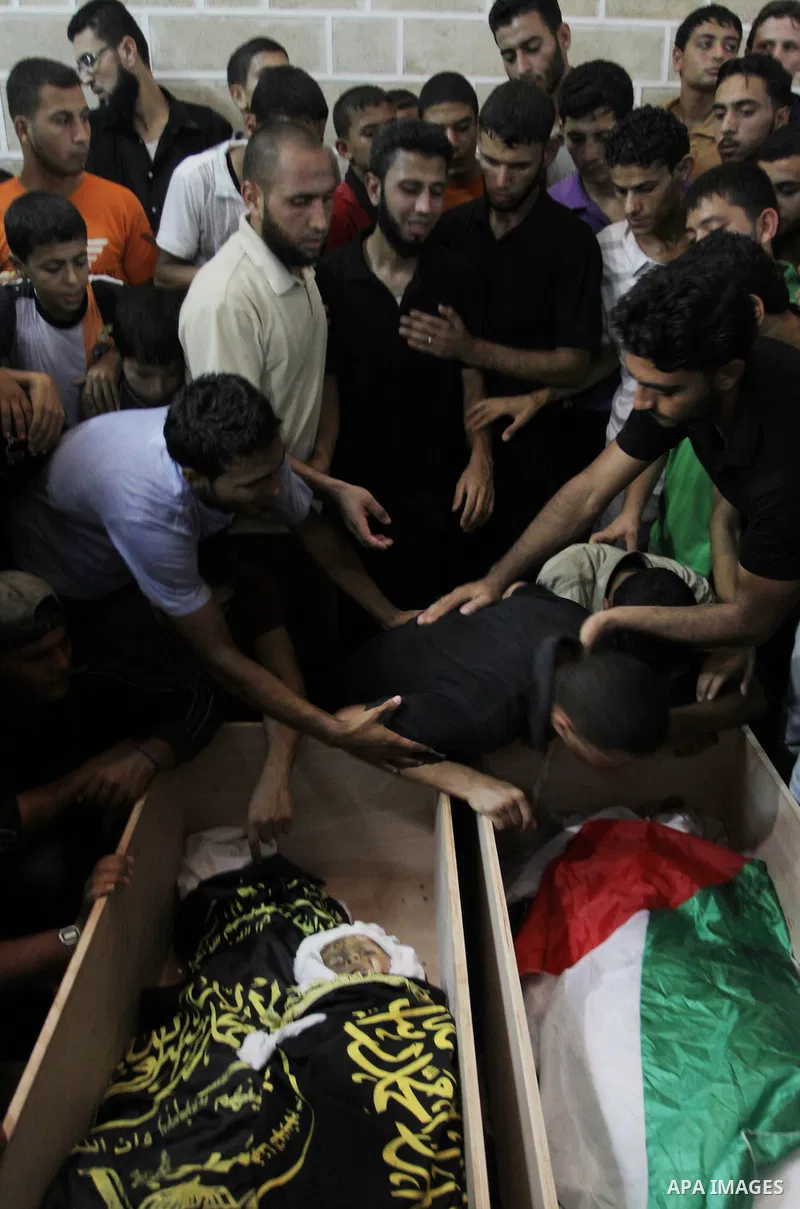 Palestinians mourn over the bodies of Moataz Qreqa, a commander of Islamic Jihad's Al-Quds Brigade, his five-year-old son Islam and his brother Munzer during their funeral in Gaza City on August 20, 2011 after all three...