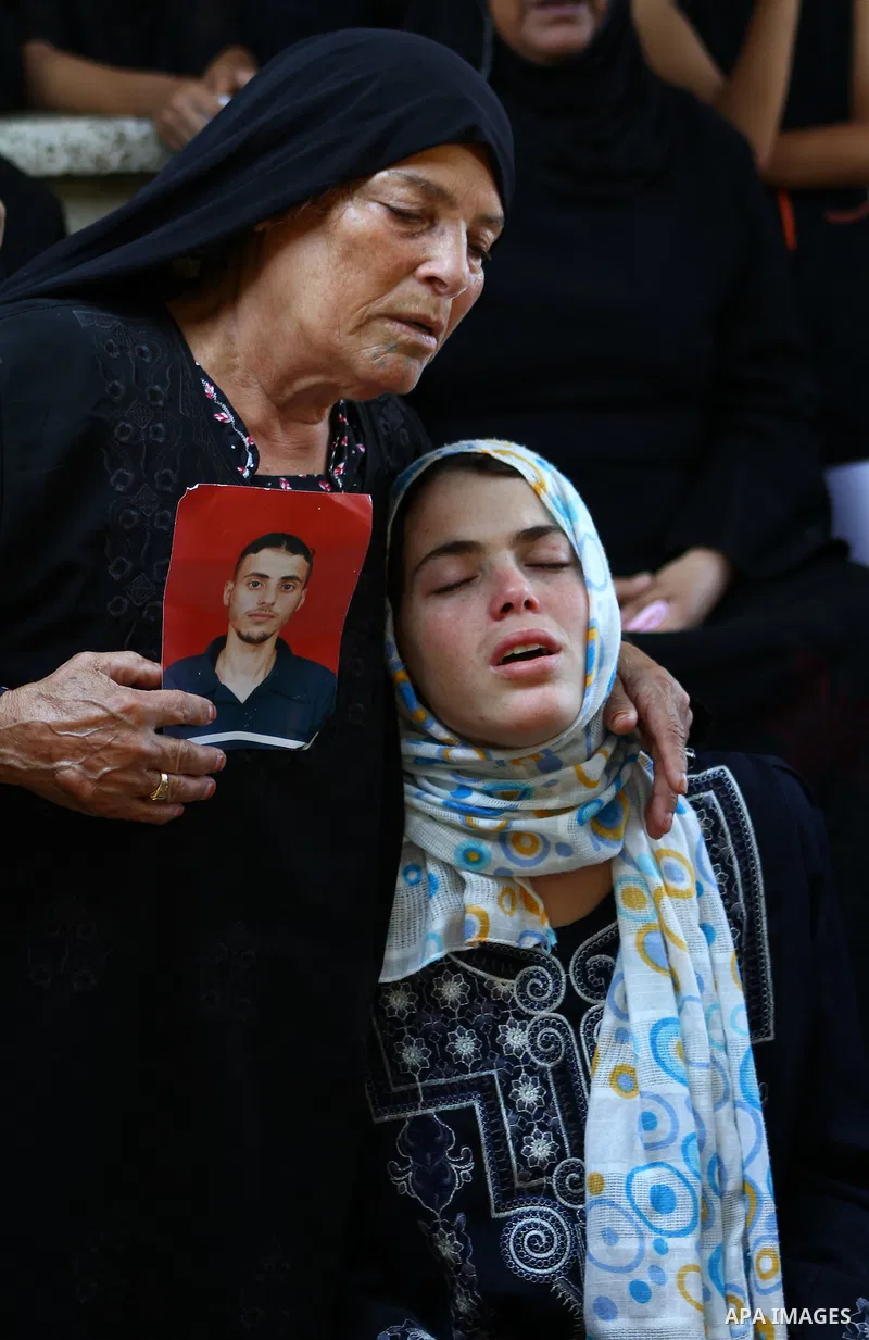 The sister of Palestinian Islamic Jihad militant Anwar Isleem (seens on the photograph) and her mother mourn during his funeral in Bureij Refugee Camp in central Gaza Strip on August 20, 2011. Anwar Isleem and Emad Abu A...