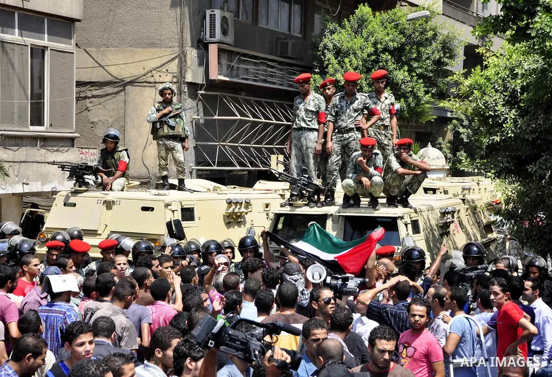 Egyptian military policemen stand guard as demonstrators wave Egyptian and Palestinian (L) flags during a protest outside the Israeli embassy in Cairo on August 20, 2011. Egypt decided to recall its ambassador from Israe...
