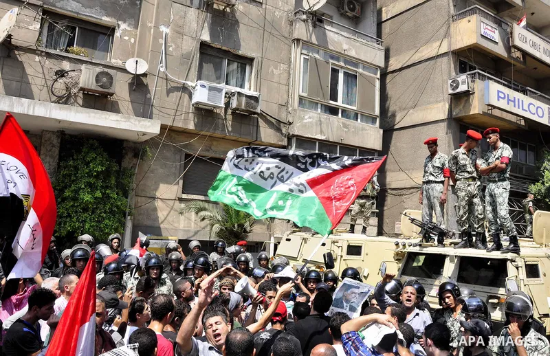 Egyptian military policemen stand guard as demonstrators wave Egyptian and Palestinian (L) flags during a protest outside the Israeli embassy in Cairo on August 20, 2011. Egypt decided to recall its ambassador from Israe...