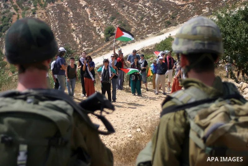 Israeli soldiers stand guard as Palestinians demonstrate along with left-wing Israelis and foreign peace activists in Beit Omar, near the West Bank city of Hebron on August 20, 2011 for the creation of a Palesitnian stat...