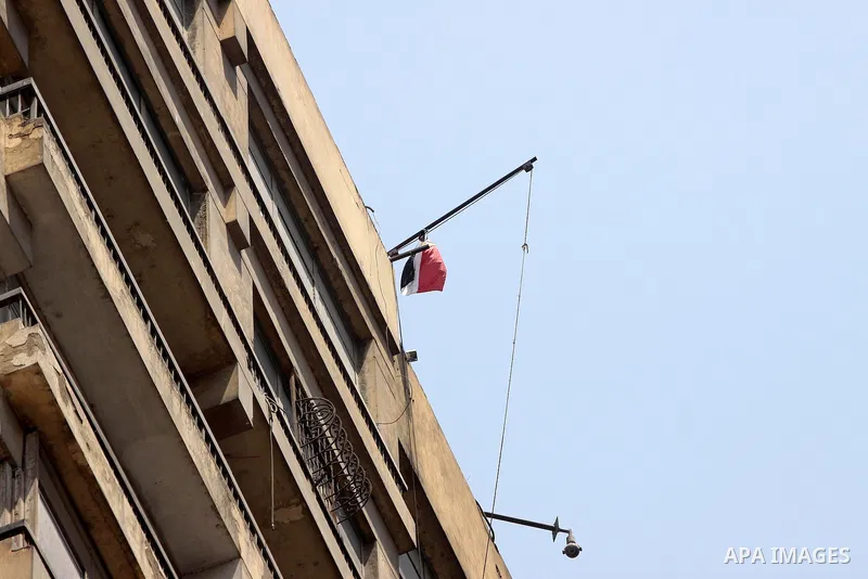 An Egyptian flag with the words "Egypt's Revolution, the 25th of January" flies over the Israeli embassy after a protester managed, at dawn, to climb 15 floors on a building where the Israeli embassy is located to remove...