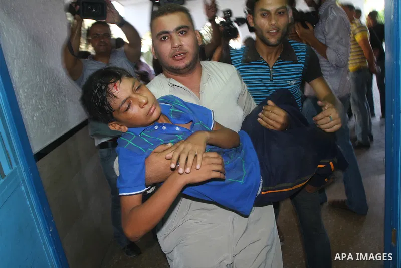 A Palestinian man carries a wounded youth into a hospital following an Israeli attack on Gaza City on August 21, 2011. Photo by Ashraf Amra