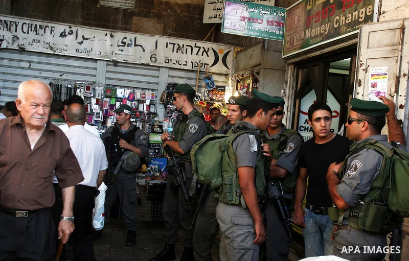 Palestinian Muslims walk past Israeli soldiers at a barricade near the Damascus Gate in East Jerusalem as Israel restricts attendance at the al-Aqsa Mosque in Jerusalem's Old City on August 21,2011.. Photo by Mahfouz Abu...