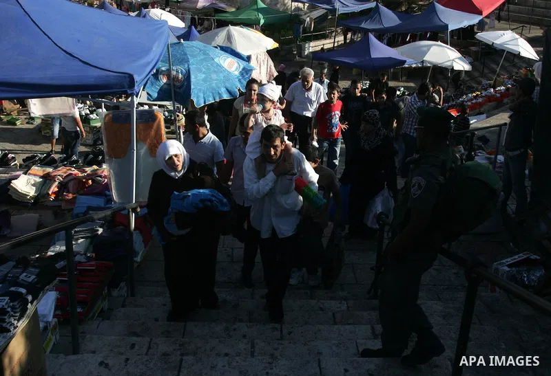 Palestinian Muslims walk past Israeli soldiers at a barricade near the Damascus Gate in East Jerusalem as Israel restricts attendance at the al-Aqsa Mosque in Jerusalem's Old City on August 21,2011.. Photo by Mahfouz Abu...