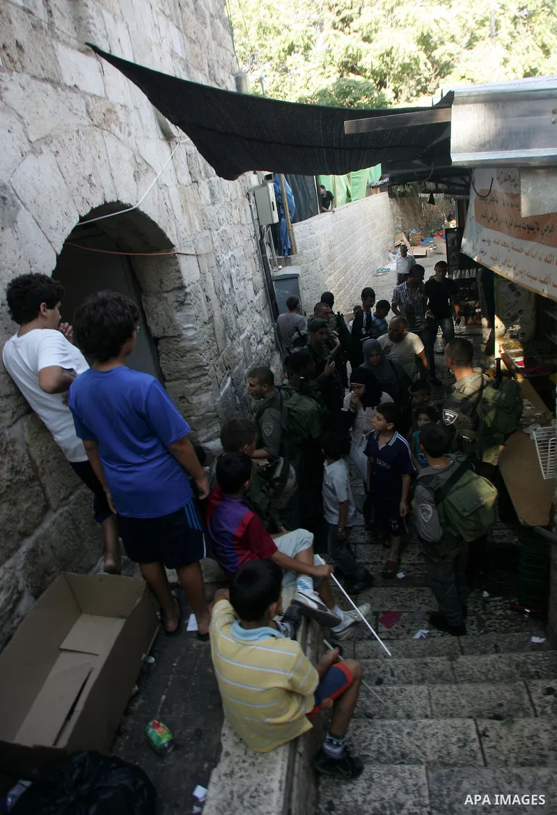 Palestinian Muslims walk past Israeli soldiers at a barricade near the Damascus Gate in East Jerusalem as Israel restricts attendance at the al-Aqsa Mosque in Jerusalem's Old City on August 21,2011.. Photo by Mahfouz Abu...