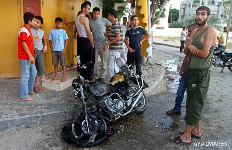Palestinians inspect a motorcycle damaged in an Israeli air strike in Deir al-Balah in the central Gaza Strip on August 24, 2011. An Israeli strike killed Ismael al-Ismar, 34, in Rafah scarcely 48 hours after militant fa...