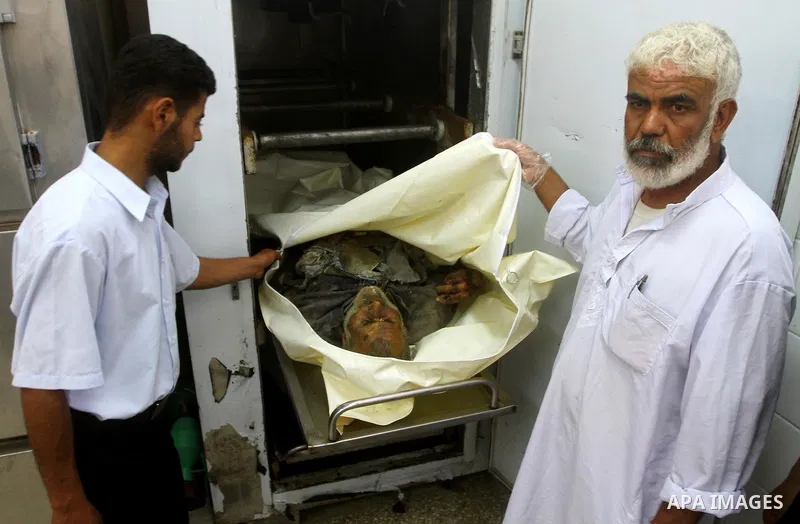 Palestinians gather around the body of Ismail Amum ,65, at Al-Aqsa hospital morgue in the central Gaza Strip on August 24,2011. Israeli air strikes killed a local commander of the Islamic Jihad militant group in the Gaza...