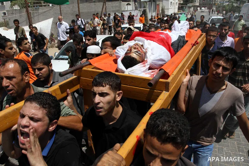 Palestinian mourners carry the body of Salama Al-Masri eighteen years-old during his funeral in the northern in Gaza Strip town of Beit-Lahia on August 25, 2011. Israeli warplanes hit a sports club run by Islamic Jihad i...