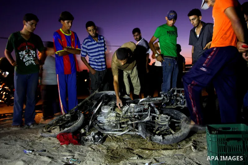 Palestinians gather around a destroyed motorcycle following an Israeli air strike killing two Islamic Jihad militants, at the main road in Jabaliya, northern Gaza Strip, Thursday, Aug. 25, 2011. Palestinian official said...