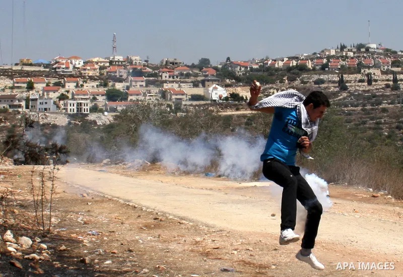 Palestinians run to seek cover from tear gas in clashes with Israeli troops during the weekly protest against the settlement of Qadomim, near the village of Kofr Qadom, west of Nablus City, in the Israeli-occupied West B...