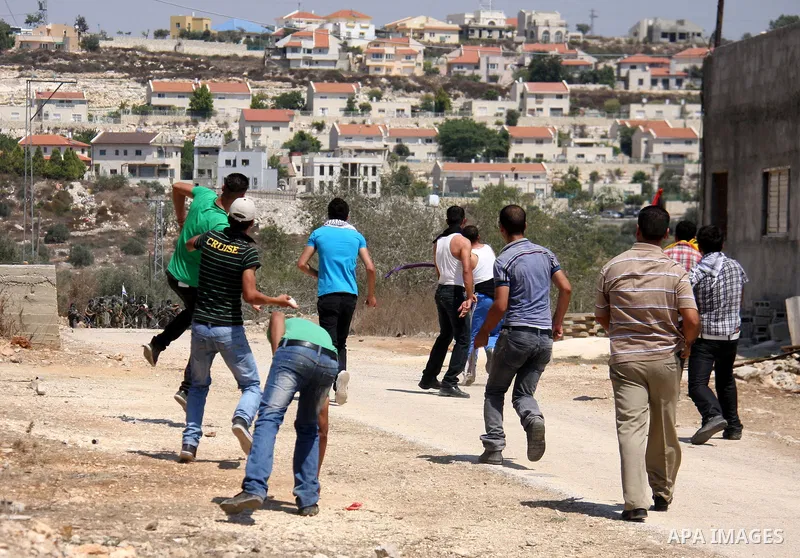 Palestinians throw stones toward Israeli troops during the weekly protest against the settlement of Qadomim, near the village of Kofr Qadom, west of Nablus City, in the Israeli-occupied West Bank on 26 August 2011. Repor...