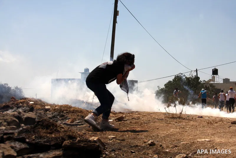 Palestinians run to seek cover from tear gas in clashes with Israeli troops during the weekly protest against the settlement of Qadomim, near the village of Kofr Qadom, west of Nablus City, in the Israeli-occupied West B...