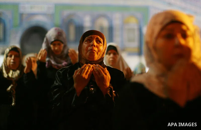 A Palestinian Muslim woman prays outside the Dome of the Rock in the Al-Aqsa Mosque compound in Jerusalem's Old City during the Islamic anniversary Lailat al-Qader, also known as the Night of Power, on August 27, 2011. P...