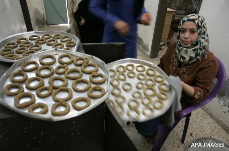 Palestinian women prepare date-filled mini cakes traditional for the Eid al-Fitr, a three-day holiday that marks the end of the fasting month of Ramadan,In their home in Rafah, southern Gaza Strip on Aug. 28, 2011. Photo...