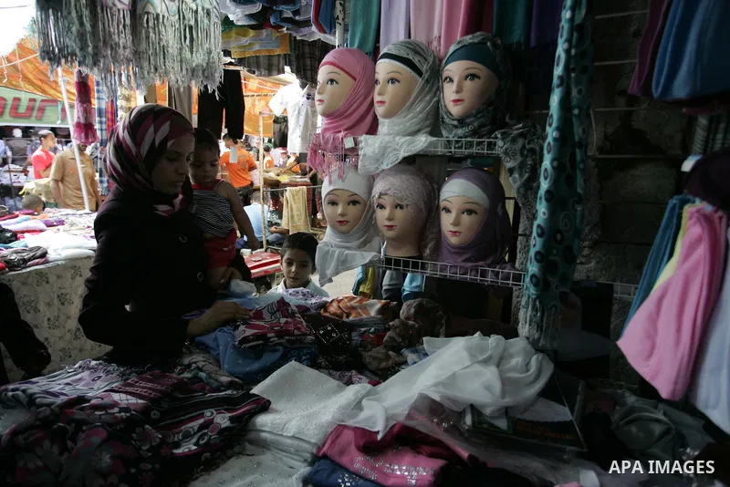 Palestinian women shop at a clothes shop as Muslims shop ahead of the Eid al-Fitr celebrations in Rafah, southern Gaza Strip on Aug. 28, 2011. Muslims in the region will celebrate the Eid al-Fitr holiday starting with th...
