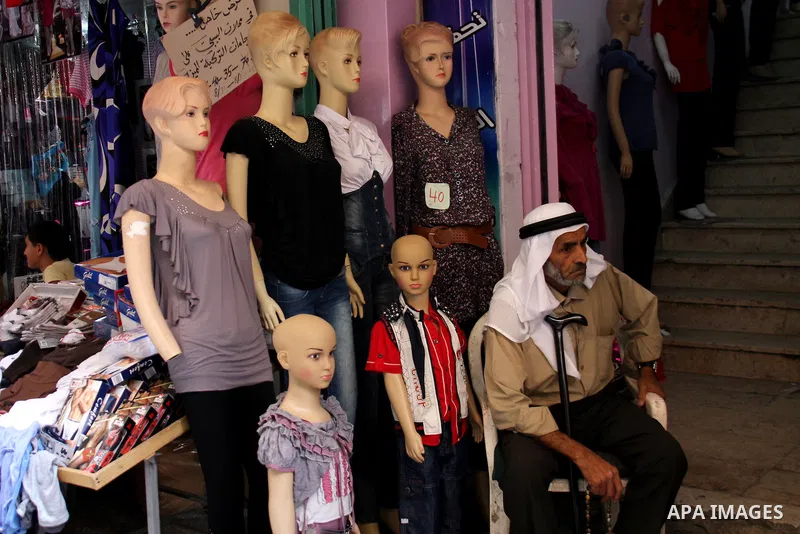 A Palestinian vendor sells clothes at a market, as Muslims shop ahead of the Eid al-Fitr celebrations in the West Bank city of Nablus on Aug. 28, 2011. Muslims in the region will celebrate the Eid Al-Fitr with the sighti...