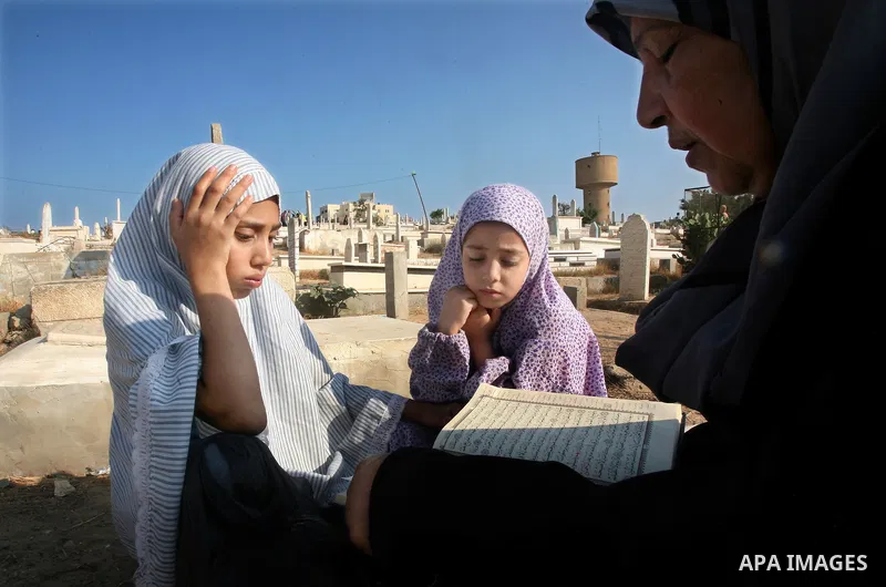 Palestinians visit their relatives' graves in a cemetery during the first day of Eid al-Fitr in the southern Gaza Strip on August 30, 2011. Eid al-Fitr marks the end of the Muslim holy month of Ramadan. Photo by Ali Jada...