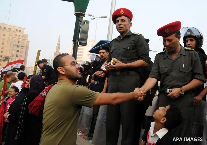 Police and military are greeted as Egyptian Muslims gather to pray, celebrating the start of the three-day feast known in Arabic Eid al-Fitr, which marks the end of the holy fasting month of Ramadan, in Tahrir Square, th...