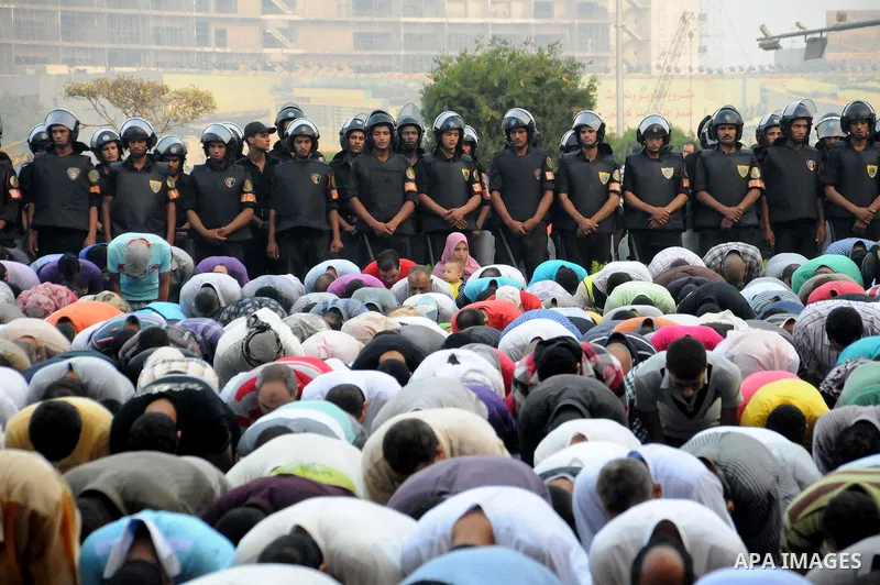 Police and military stand guard as Egyptian Muslims gather to pray, celebrating the start of the three-day feast known in Arabic Eid al-Fitr, which marks the end of the holy fasting month of Ramadan, in Tahrir Square, th...