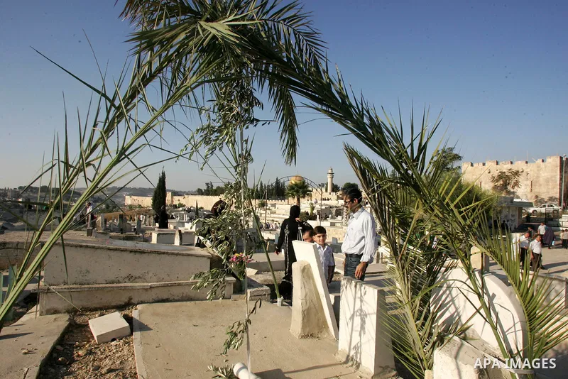 A Palestinian family gather to pray over the graves of loved ones in a cemetery near the Al-Aqsa Mosque compound in Jerusalem's Old City on August 30, 2011, marking the first day of Eid al-Fitr and the end of the holy fa...