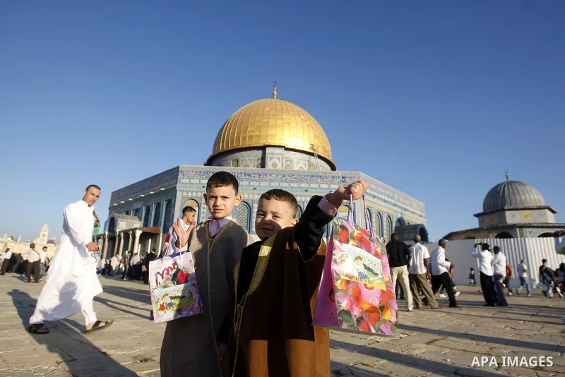 Palestinians walk after performing the morning Eid Al-Fitr prayer in front of the Dome of Rock at the Al-Aqsa Mosque compound, Islam's thrid most holy site, in Israeli annexed East Jerusalem, on August 30, 2011, marking...