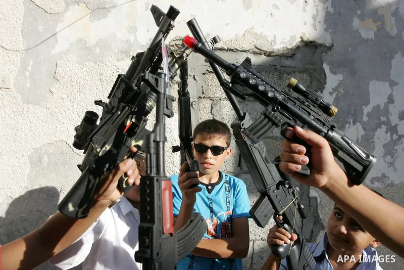 Palestinian boys play with toy guns on the third day of the Eid al-Fitr holiday in Rafah Refugee Camp in the southern Gaza Strip on 01 September 2011. Eid marks the end of the holy month of Ramadan. Photo by Abed Rahim K...