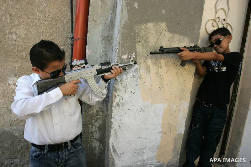 Palestinian boys play with toy guns on the third day of the Eid al-Fitr holiday in Rafah Refugee Camp in the southern Gaza Strip on 01 September 2011. Eid marks the end of the holy month of Ramadan. Photo by Abed Rahim K...