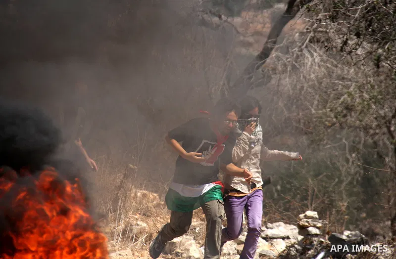 Palestinian demonstrators pass burning tires as they protest against the closure of a road during the second Intifada (uprising) by Jewish settlers from the nearby settlement of Kadumim, on September 2, 2011 in the West...