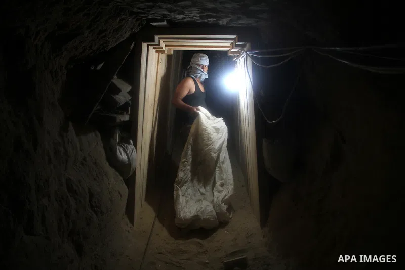 Palestinian tunnel digger, wearing a mask to conceal his identity, removes sand in a bucket from a tunnel underground in Rafah, in the southern Gaza Strip, on the border with Egypt on Sep. 4, 2011. Egyptian military Corp...