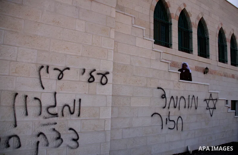 A Palestinian man looks at Hebrew writing on the wall of a mosque in the West Bank village of Qusra, near Nablus September 5, 2011. Jewish settlers set fire to part of the mosque in the occupied West Bank on Monday, Pale...