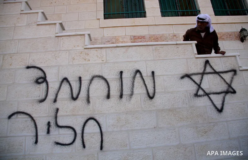 A Palestinian man looks at Hebrew writing on the wall of a mosque in the West Bank village of Qusra, near Nablus September 5, 2011. Jewish settlers set fire to part of the mosque in the occupied West Bank on Monday, Pale...