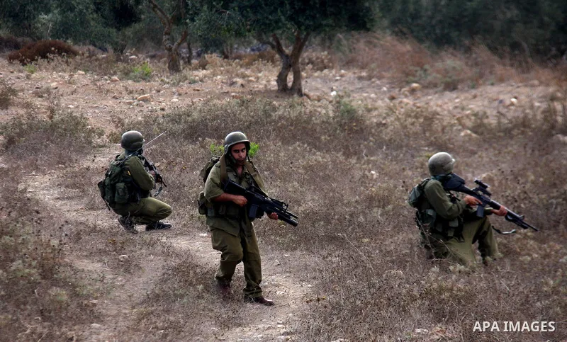 Israeli soldiers patrol in a field as villagers try to extinguish fires in a olive grove and fields which according to the local Palestinian villagers was started by settlers from a near by Jewish settlement close to the...