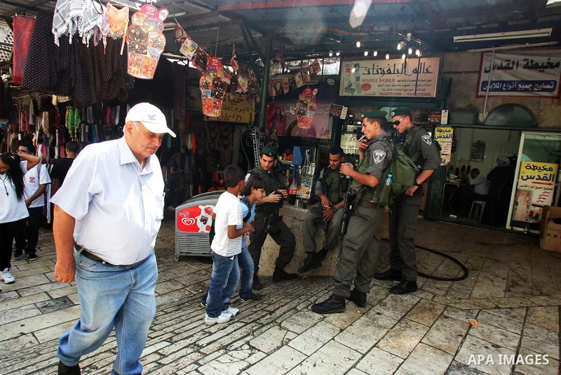 Palestinian students walk past Israeli soldiers standing guard at the main market in Jerusalem's old city on Sep. 5,2011, after they returned back from their school on the second day of the new studing year,. Photo by Ma...